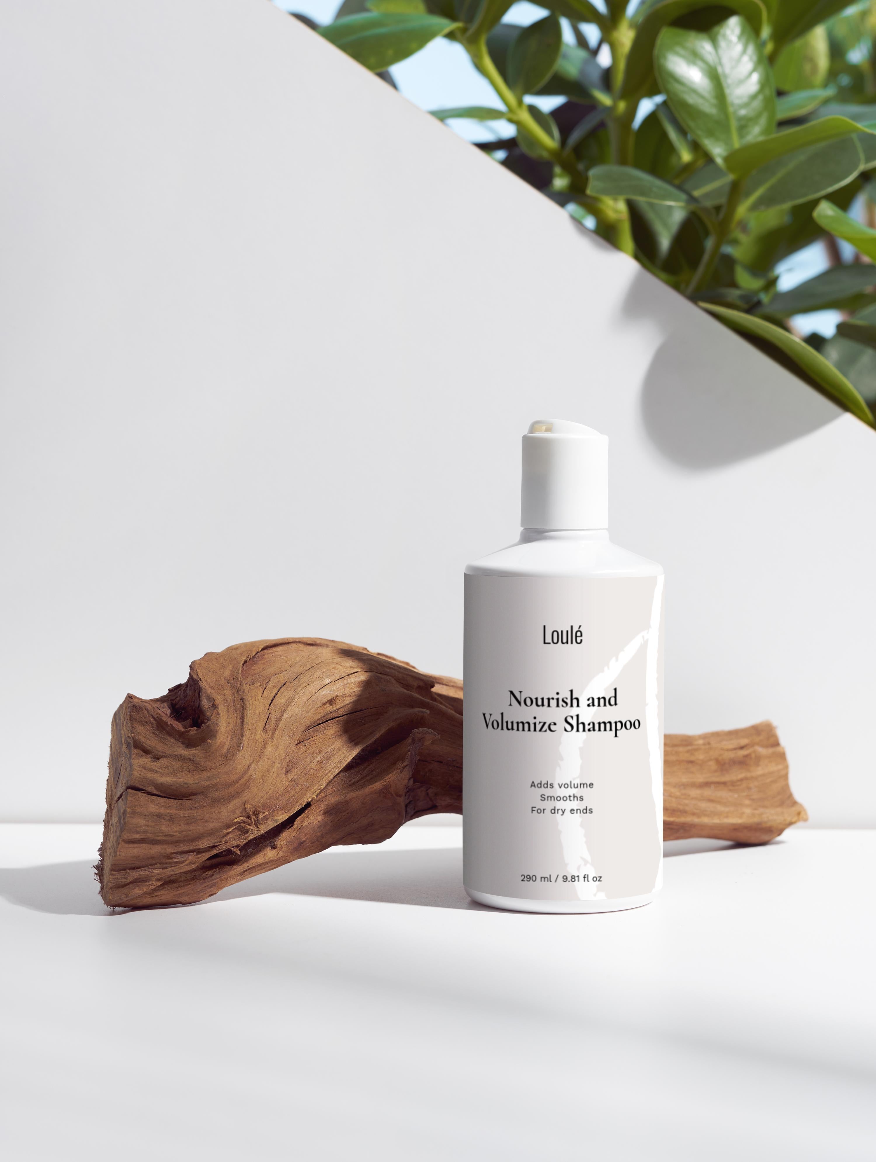 Loulé Skin Nourish and Volumize Shampoo in sleek white bottle with natural wood accent, ideal for dry ends and adding volume to hair.