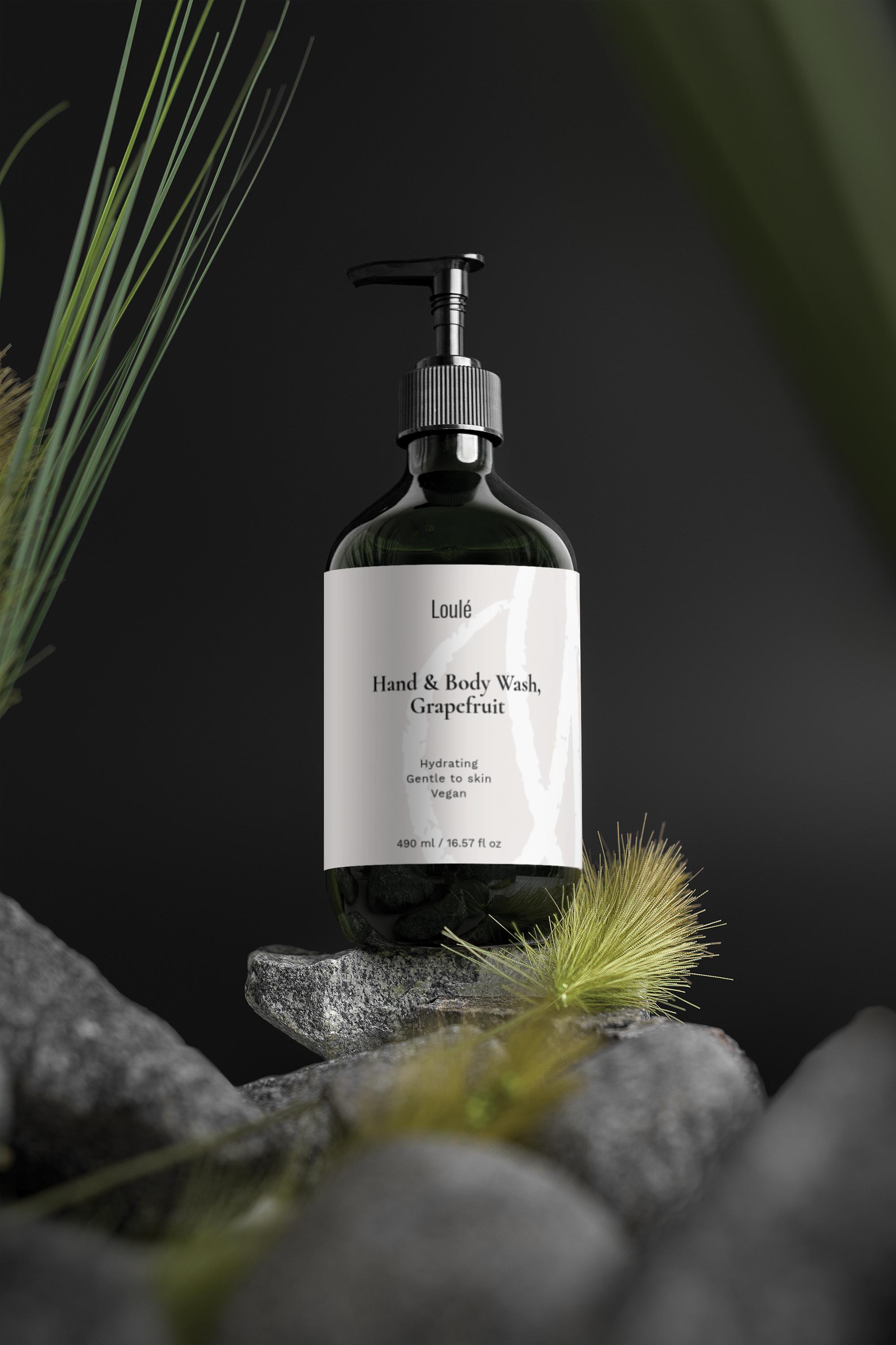 Hand & Body Wash, Grapefruit in dark green pump bottle with minimalist white label, placed on natural stones with grass, ideal for gentle skin cleansing.