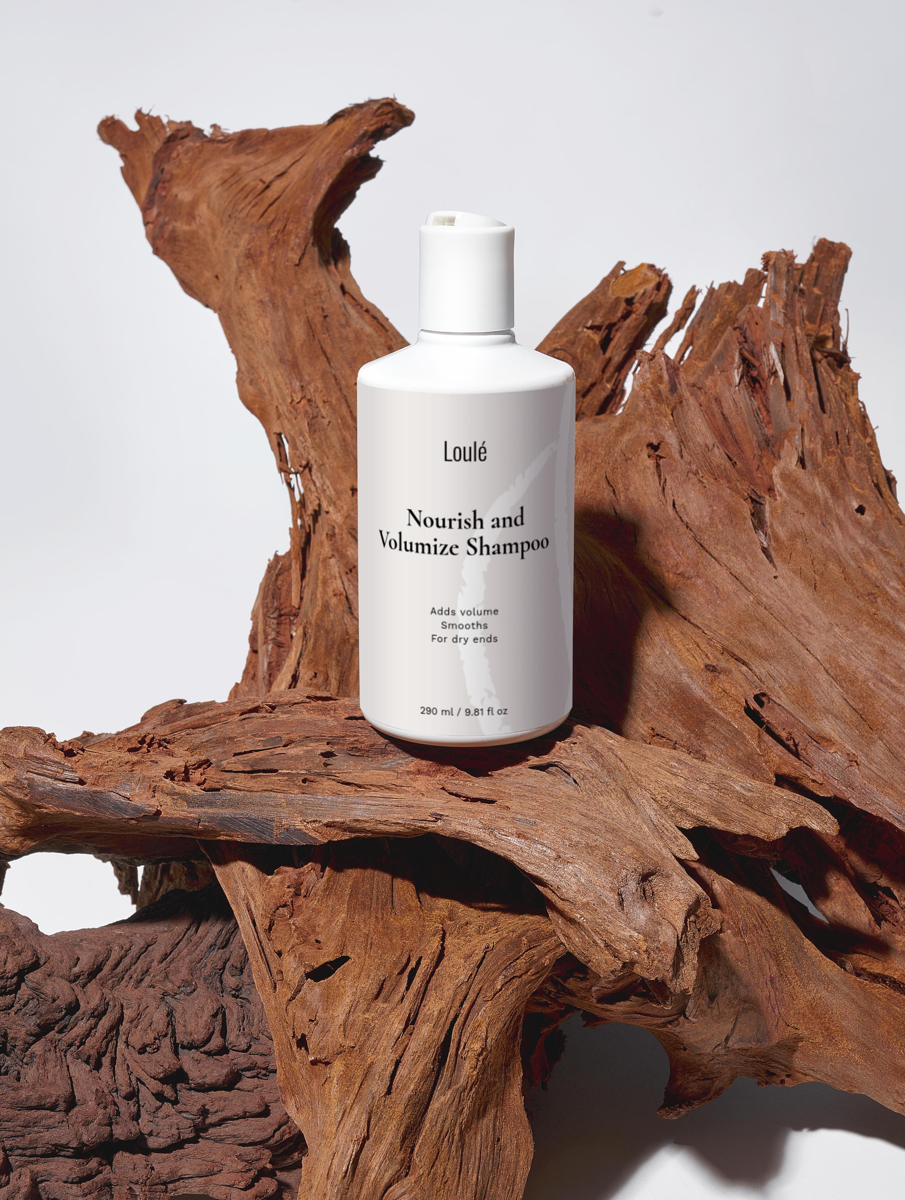 Loulé Skin Nourish and Volumize Shampoo in white bottle placed on natural wood, ideal for dry ends and adding volume with wheat protein and betaine.
