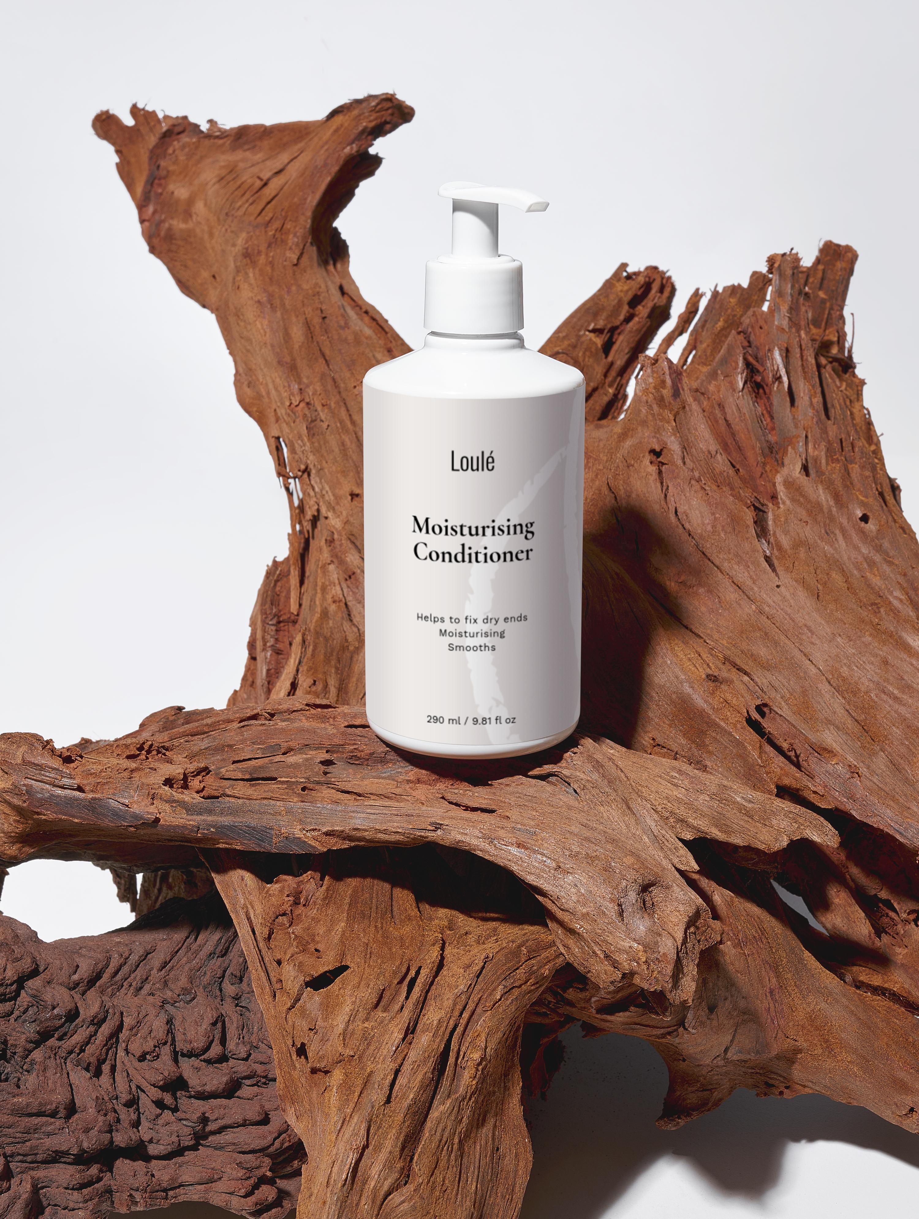 Loulé Moisturising Conditioner with aloe juice, argan oil, and wheat protein on rustic wood background. Ideal for dry ends and lack of volume.